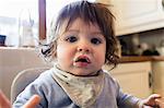 Cute baby with food on his mouth in the kitchen