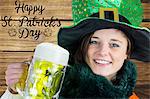 Woman holding beer next to st patricks day greeting on wooden background