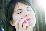 Woman holding apple against her face, eyes closed