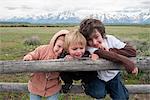 Children leaning against fence in Grand Teton National Park, Wyoming, USA