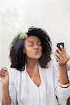Woman blowing kiss at smartphone while doing video chat