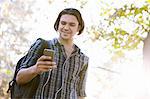 Low angle view of young man holding smartphone looking down smiling