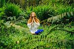 Young woman practicing yoga in lotus position in forest