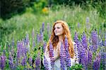 Serene young woman meditating with hands together amongst purple wildflowers