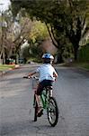 Boy riding bicycle in middle of road