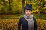 Portrait of mid adult woman wearing trilby and scarf in autumn forest