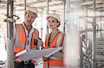 Female and male builders with blueprint on construction site