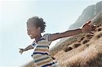 A girl with arms outstretched in a gesture of freedom and excitement, leaning into the breeze.