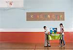 A boy and girl carrying a table with a presentation on solar power, at a Green Science Fair event.