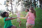 A group of four girls holding hands and dancing outside.