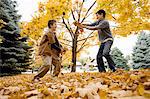 Two boys playing and throwing autumn leaves in the air and at each other.
