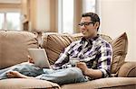 A man sitting on a sofa using a digital tablet and holding a credit card.