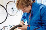 A young man working in a cycle shop, repairing a bicycle.