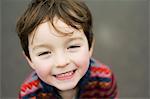 A boy looking up at the camera and smiling.