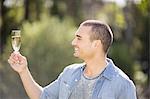 Smiling man looking at a glass of champagne in garden