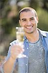 Smiling man holding a glass of champagne in garden