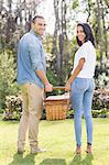 Happy couple posing with picnic basket in the garden