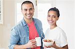 Smiling couple eating breakfast together in the kitchen at home