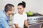 Young couple using laptop together in the kitchen at home