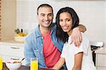 Smiling couple embracing and eating breakfast in the kitchen at home