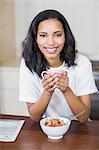 Smiling woman having breakfast in the kitchen at home