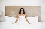 Smiling woman sitting on the bed at home in the bedroom