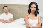 Upset couple sitting on bed after having an argument at home