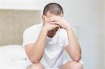 Upset man sitting on bed after having an argument at home