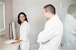 Smiling couple in bathrobe looking at mirror in bathroom