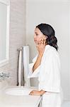 Focused brunette looking in mirror in bathroom