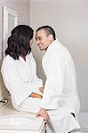 Smiling couple in bathrobe about to kiss in bathroom