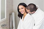 Smiling couple wearing bathrobe in bathroom