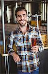 Happy brewer showing pint of beer at the local brewery