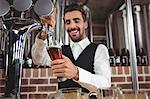 Handsome barman pouring beer in a pub