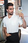 Handsome man holding a glass of wine in a brewery