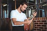 Winemaker examining bottle of white wine in a brewery