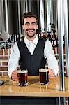 Handsome barman giving two beers in a pub