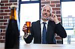 Businessman on the phone holding a beer in a pub