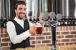 Handsome barman pouring a pint of beer in a pub
