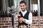 Handsome barman pouring a beer in a pub