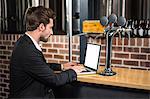 Handsome businessman using laptop in a pub