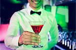 Bartender serving glass of cocktail at bar counter in bar