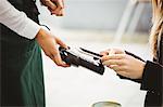 Woman paying with mobile phone in cafe