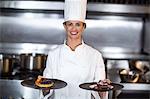 Chef showing plates of dessert in a commercial kitchen