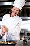 Chef piping icing on biscuits in a commercial kitchen