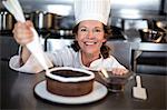 Chef piping icing on cake in a commercial kitchen