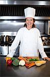 Chef slicing vegetables on wooden board in a commercial kitchen