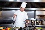 Happy chef using tablet pc while cooking in a commercial kitchen