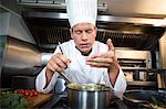 Happy chef smelling his dish in a commercial kitchen