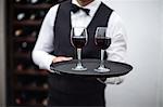 Waiter holding tray of red wine in a commercial kitchen